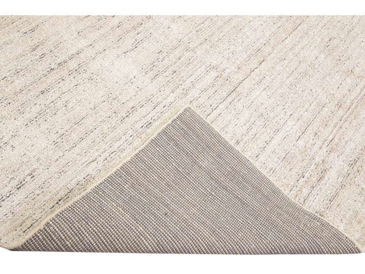 Beautiful Modern Delino hand-loom wool beige field. This piece has a gorgeous all-over solid design.  This rug measures 5' x 8'.